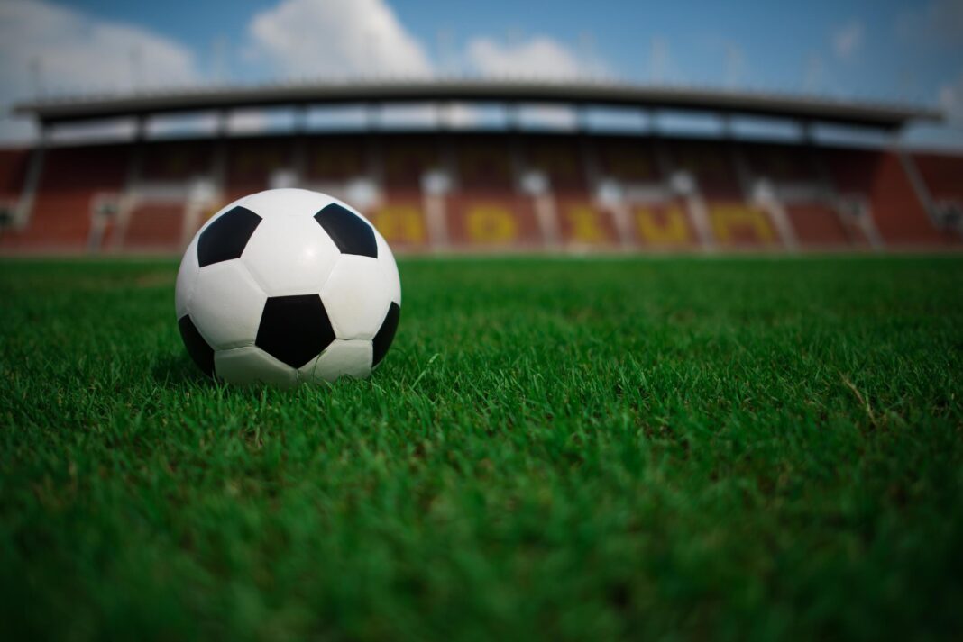 -un-pallone-da-calcio-su-erba-con-sfondo-stadio-foto